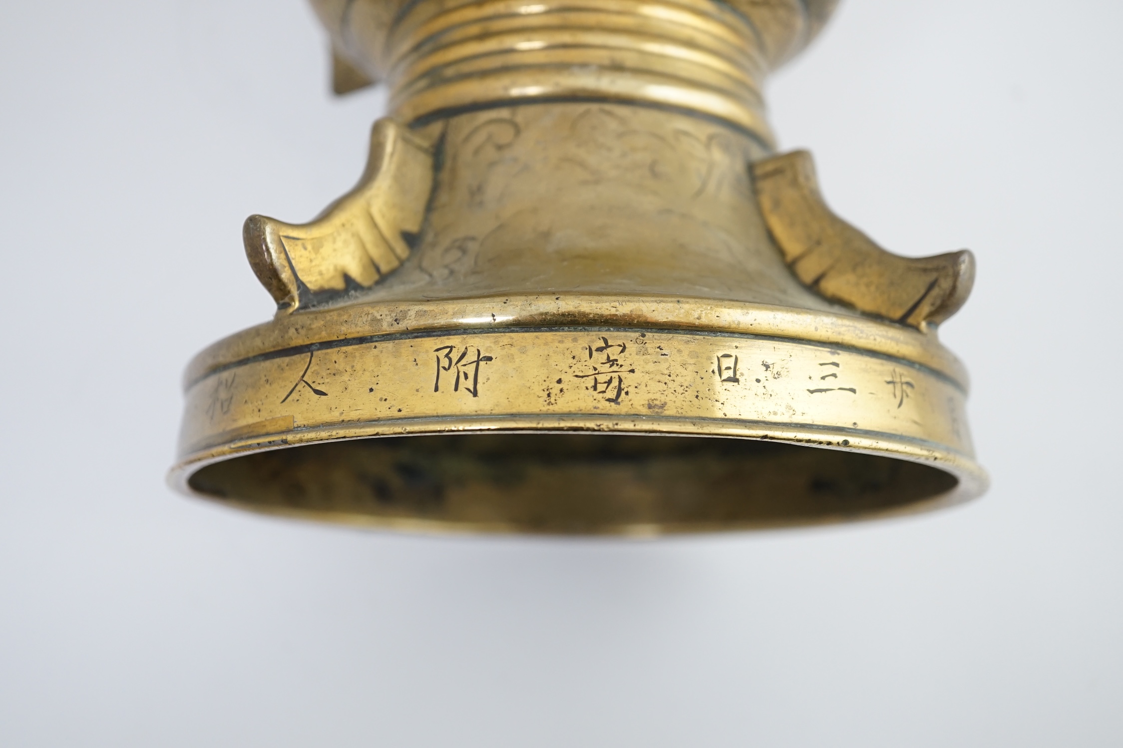 A Chinese inscribed archaistic bronze altar vase, gu, 19th century, the foliate engraved vase applied with raised fins and cast in relief with lion-dogs, the base engraved with an inscription, 33.7cm high. Condition - go